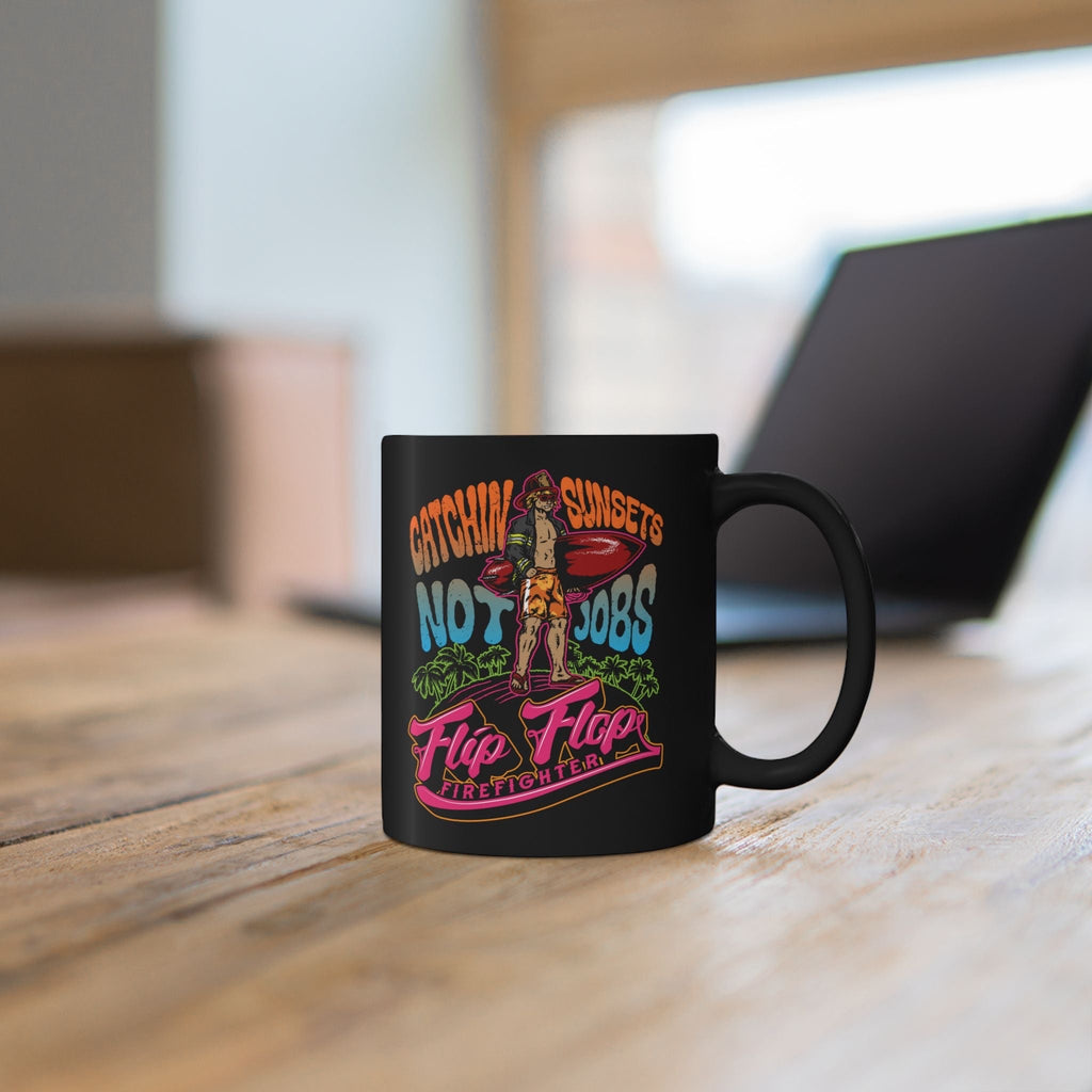 Flip Flop Firefighter black ceramic coffee mug with Catchin' Sunsets graphic print on a wooden desk.