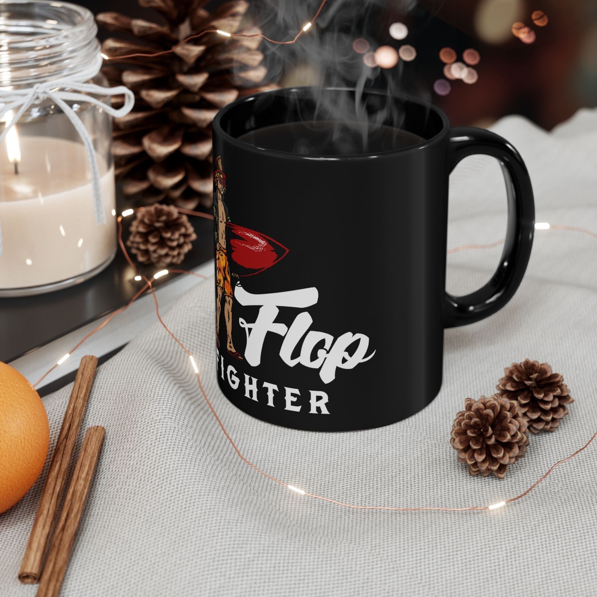 Flip Flop Firefighter glossy black ceramic coffee mug with surfer graphic, displayed on a cozy table with pinecones.