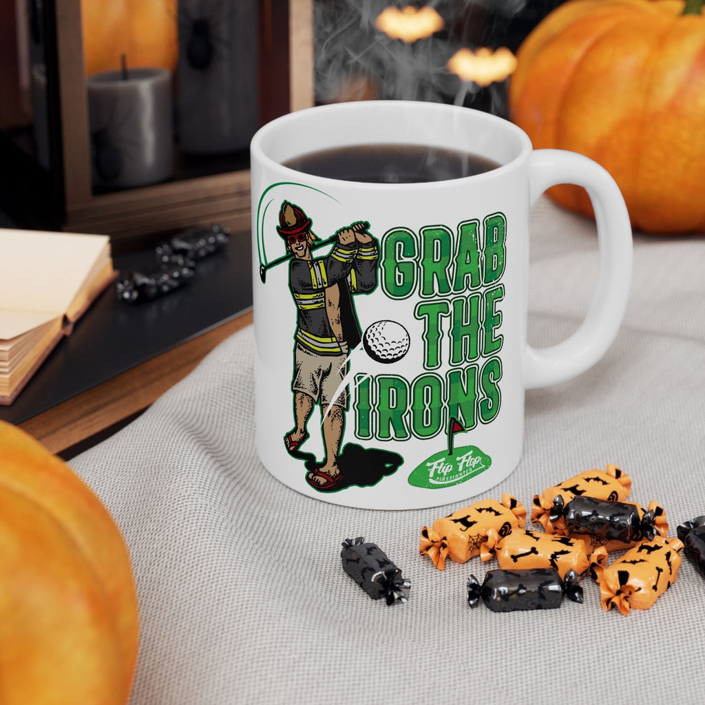Flip Flop Firefighter white ceramic coffee mug featuring a firefighter golfing graphic and Grab The Irons text.