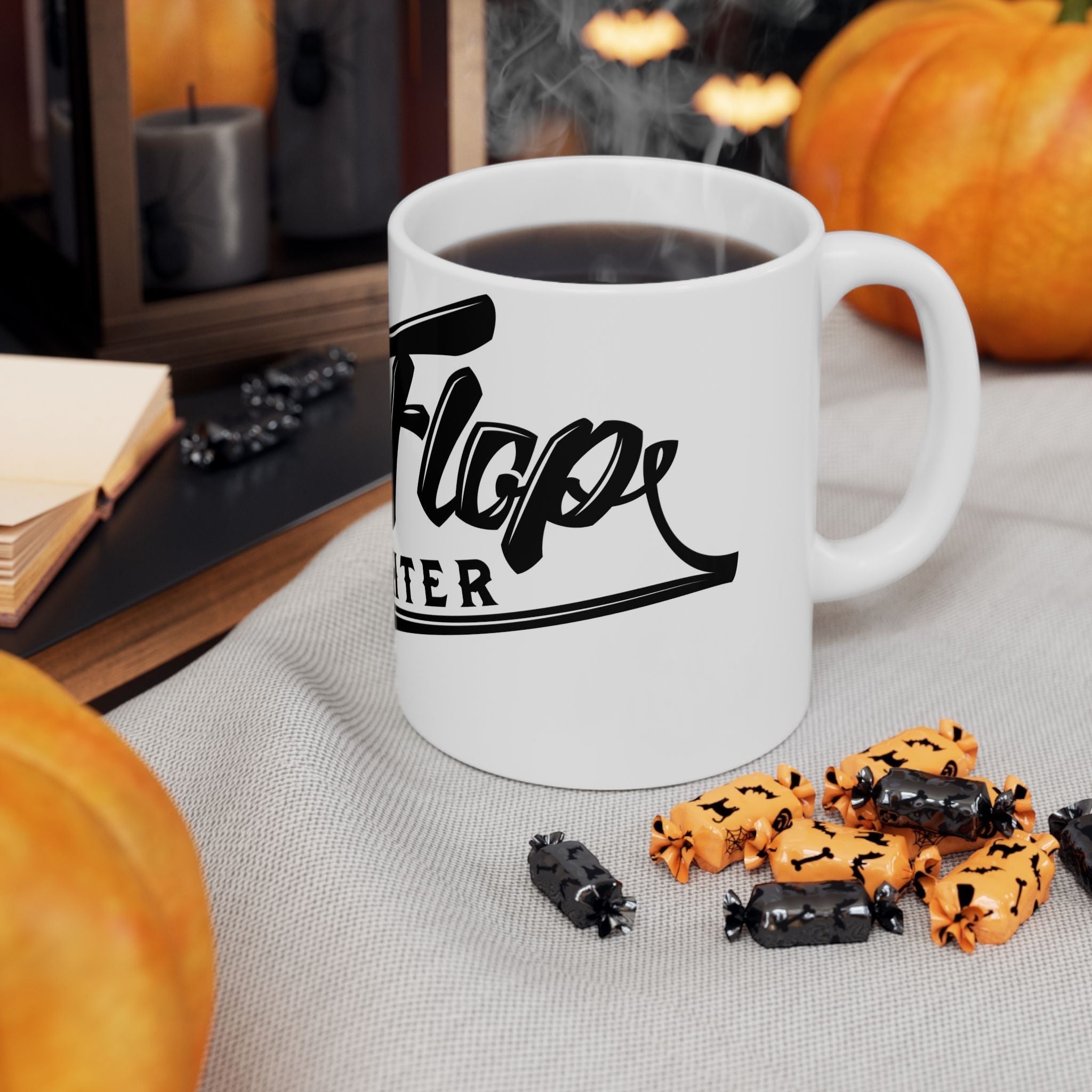 Flip Flop Firefighter glossy white ceramic coffee mug with black logo, set on a table with pumpkins and Halloween candy