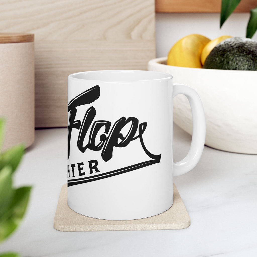 Flip Flop Firefighter white ceramic coffee mug with black logo on a kitchen counter with a coaster.