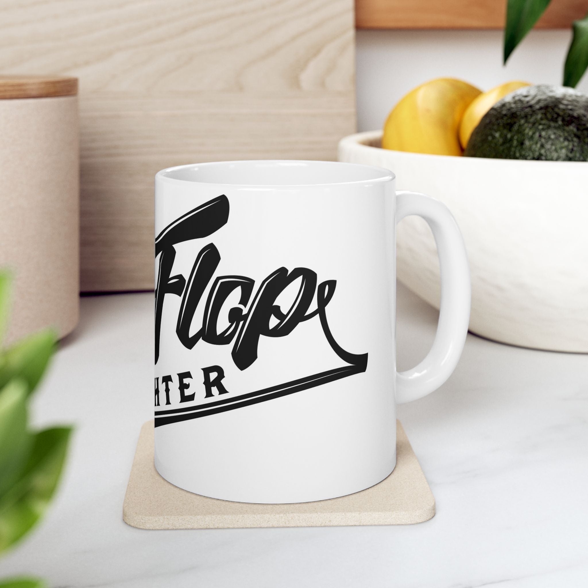 Flip Flop Firefighter white ceramic coffee mug with black logo on a kitchen counter with a coaster.